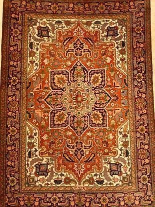 A rug with a floral pattern on it is hanging on a wall.