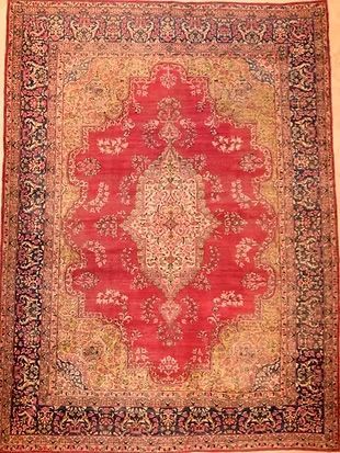 A red and gold rug with a black border is hanging on a wall.