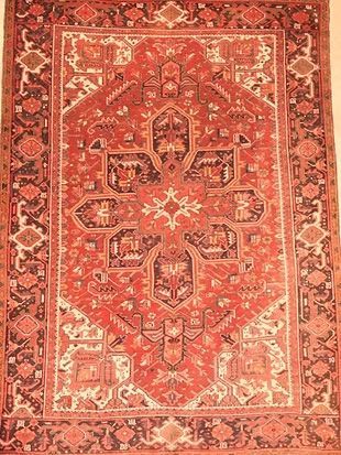 A red rug with a pattern on it is hanging on a wall.