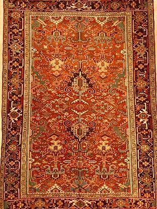 A rug with a floral pattern on it is hanging on a wall.
