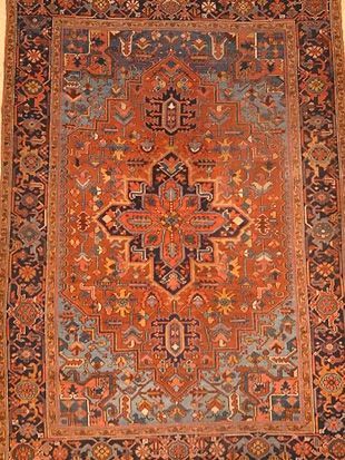 A rug with a floral pattern on it is hanging on a wall.