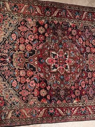 A rug with a floral pattern is hanging on a wall.