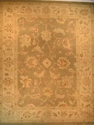 A rug with a floral pattern on it is hanging on a wall.