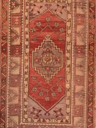 A red rug with a geometric pattern and the letter k on it