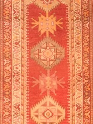 A red and orange rug with a geometric pattern on it