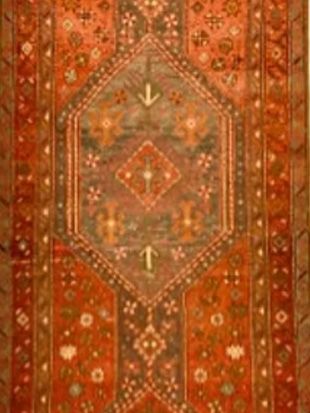 A rug with a pattern on it is hanging on a wall.