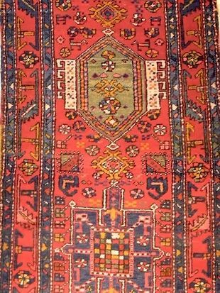A red rug with a blue border has a cross on it
