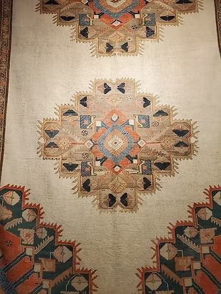 A rug with a geometric pattern on it is hanging on a wall.