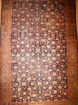 A rug with a floral pattern on it is hanging on a wall.