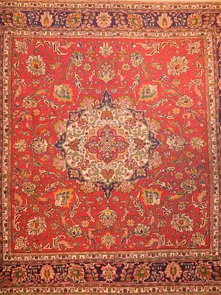 A close up of a red rug with a floral pattern on it.