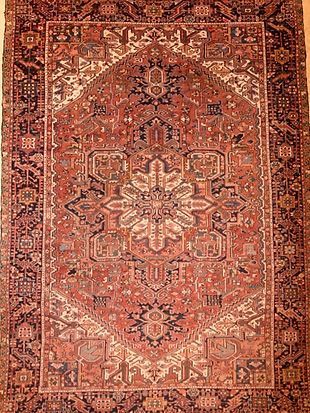 A rug with a pattern on it is hanging on a wall.