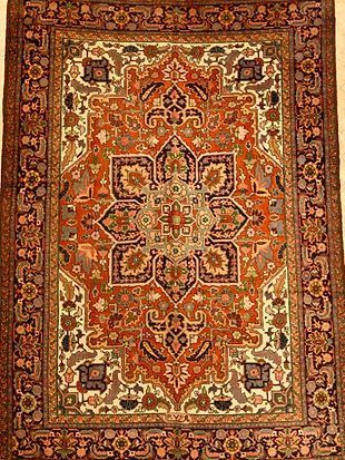 A rug with a floral pattern on it is hanging on a wall.