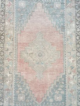 A close up of a pink and blue rug with a pattern on it.