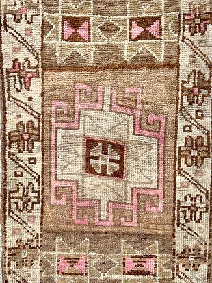 A close up of a rug with a pink and brown pattern on it.