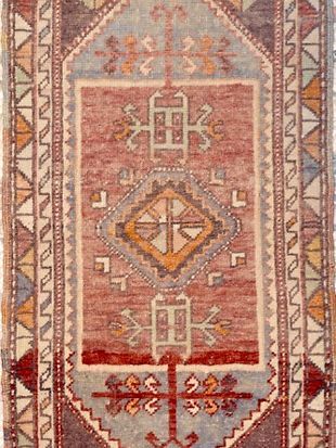A rug with a geometric pattern on it is on a white background.