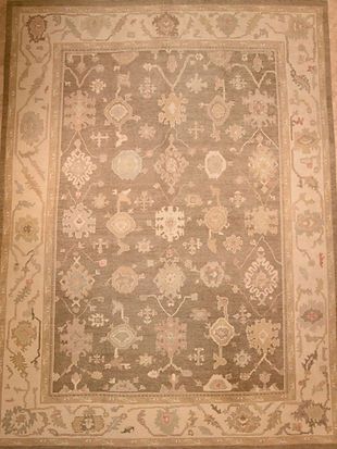 A rug with a floral pattern on it is hanging on a wall.