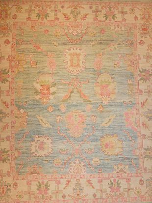 A blue and pink rug with a floral pattern on it is on a wall.