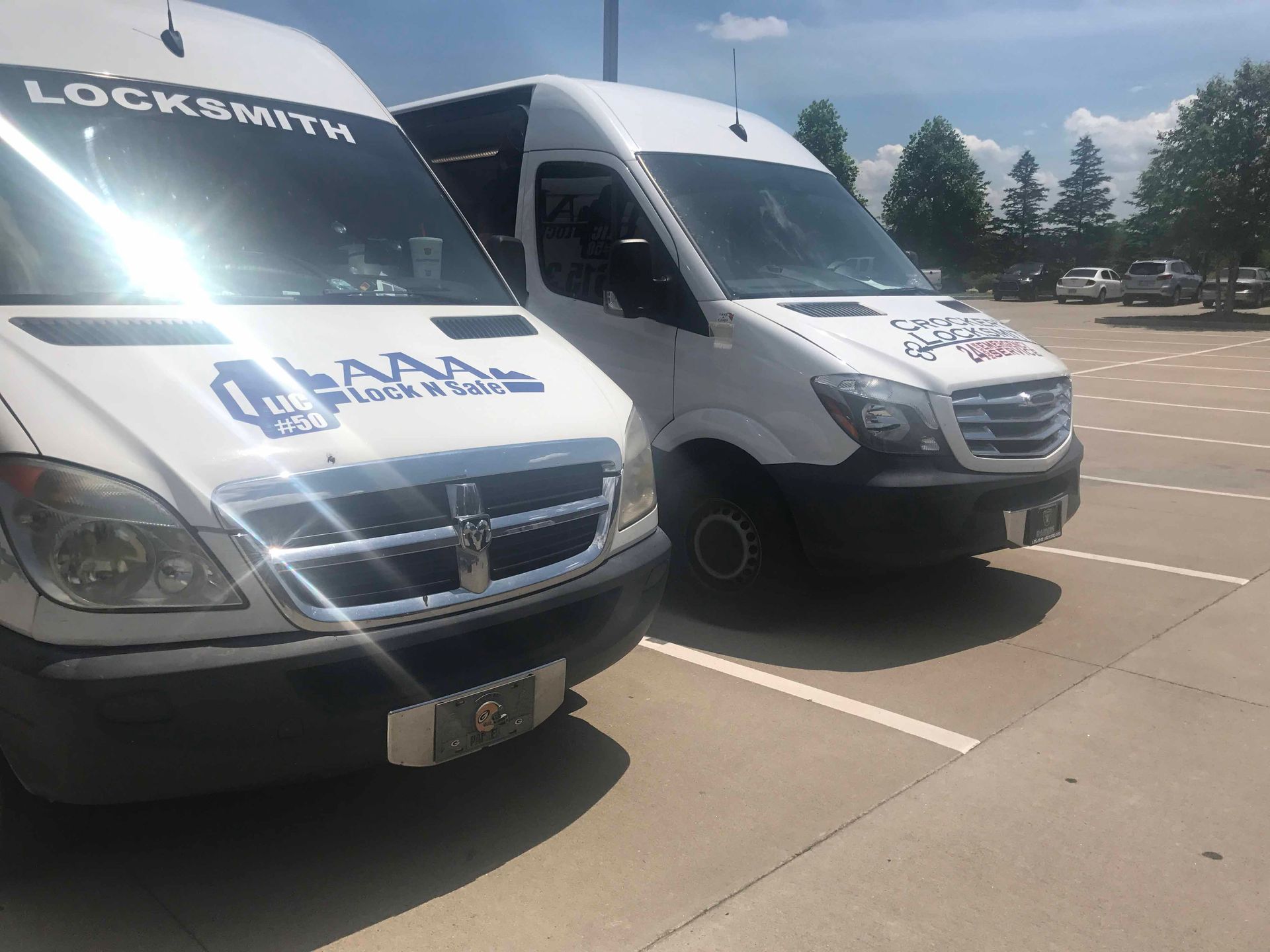 Two white locksmith vans parked in a sunny lot.