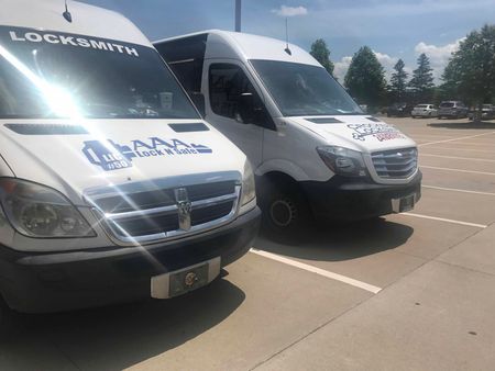 Two white locksmith vans parked in a sunny lot.