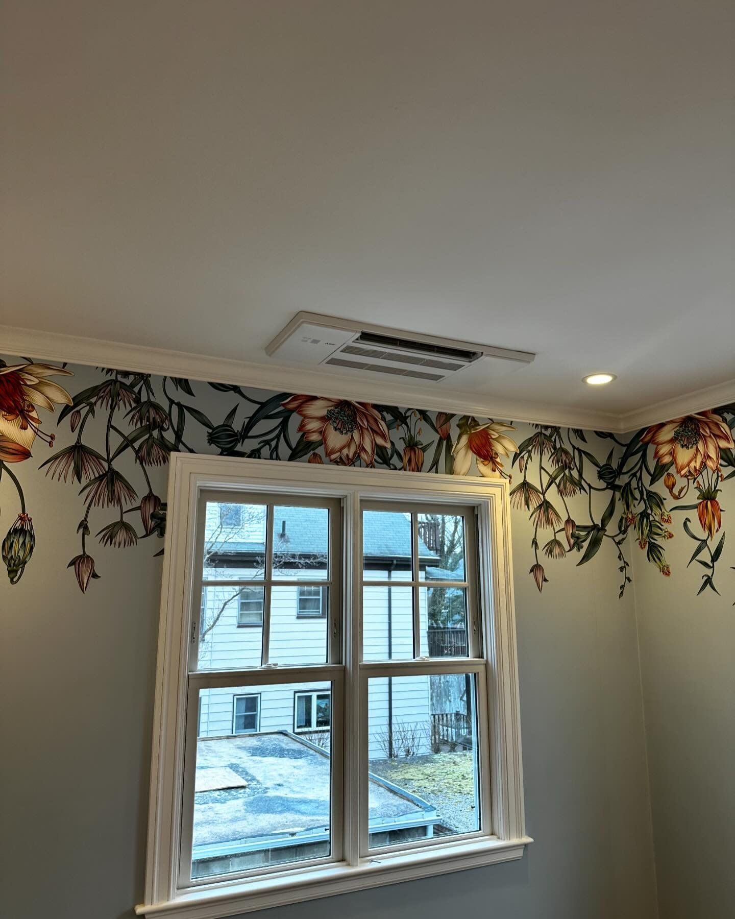 a room with a window and a floral wallpaper on the wall