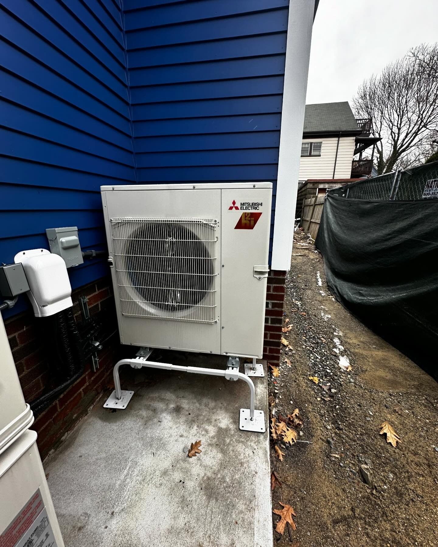 a white air conditioner is sitting on the side of a blue house
