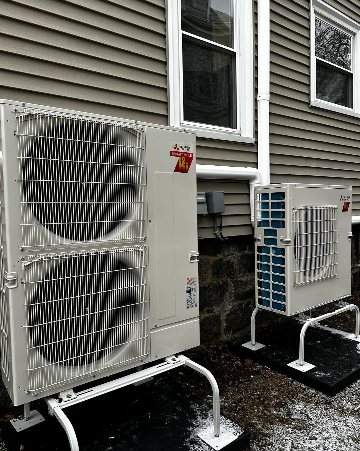 two air conditioners are sitting outside of a house