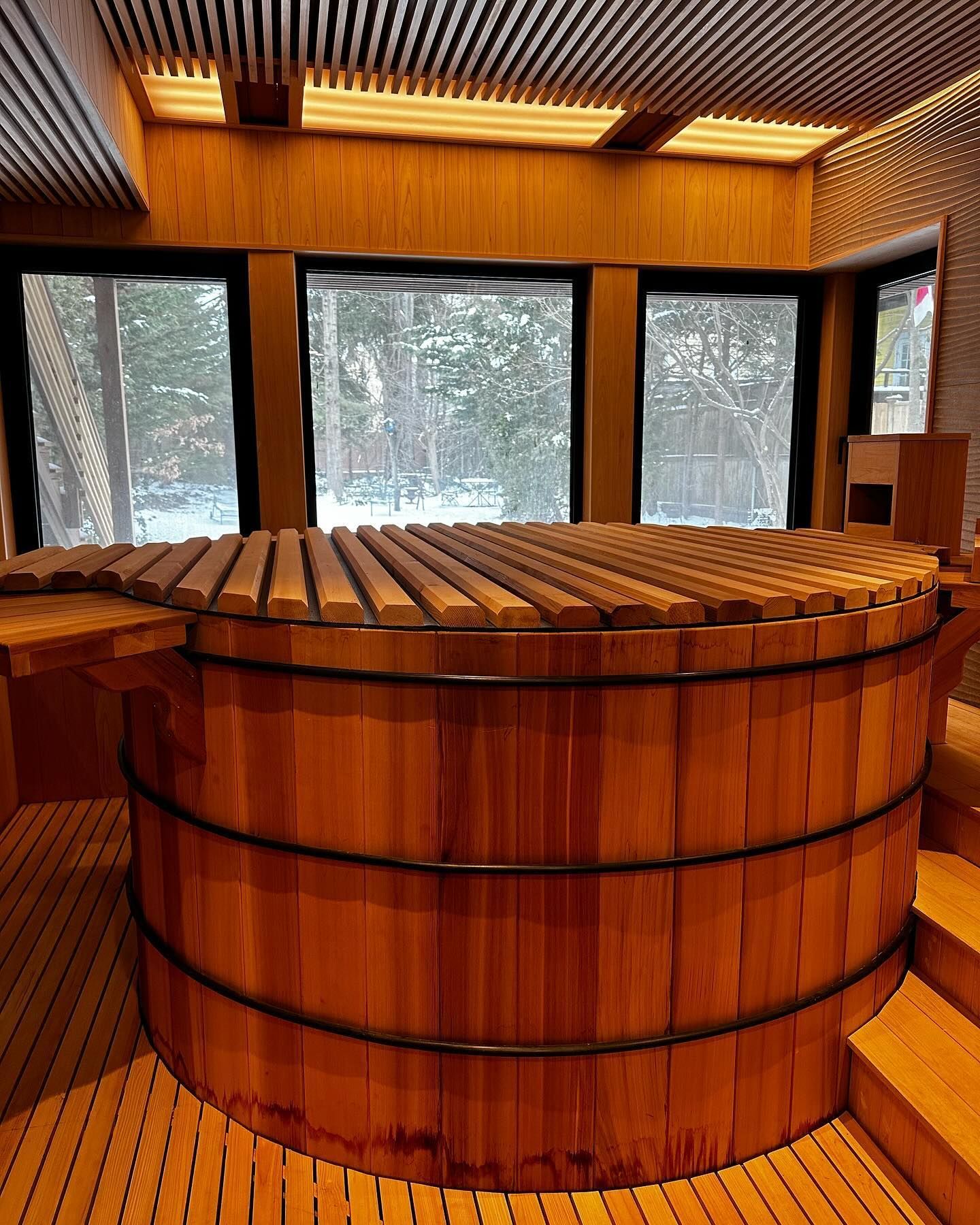 a large wooden tub is sitting in a room with lots of windows