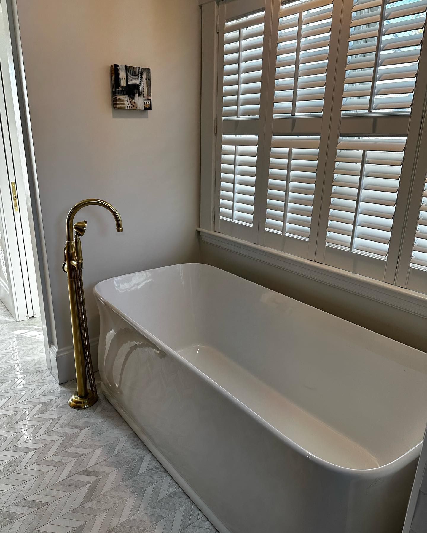 a bathroom with a bathtub and shutters on the windows