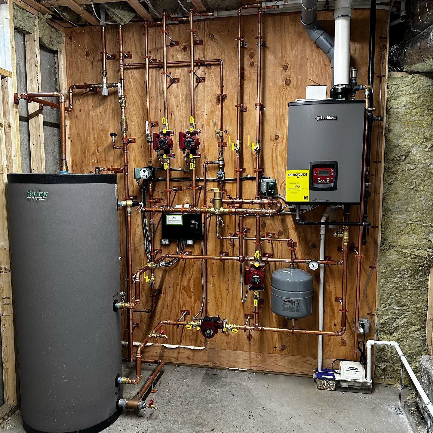 a room with a water heater and copper pipes on the wall
