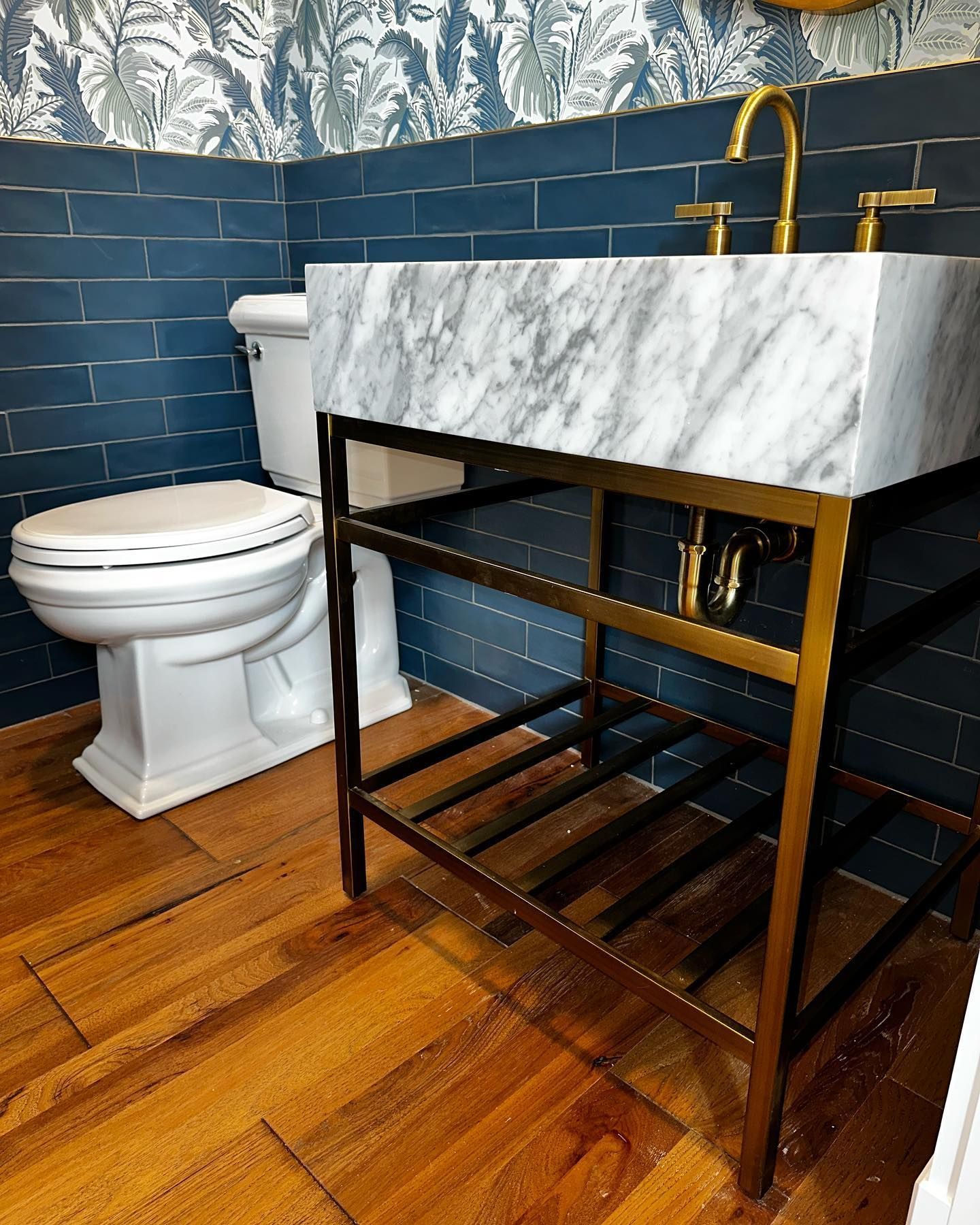 a bathroom with a toilet, sink, and wooden floor