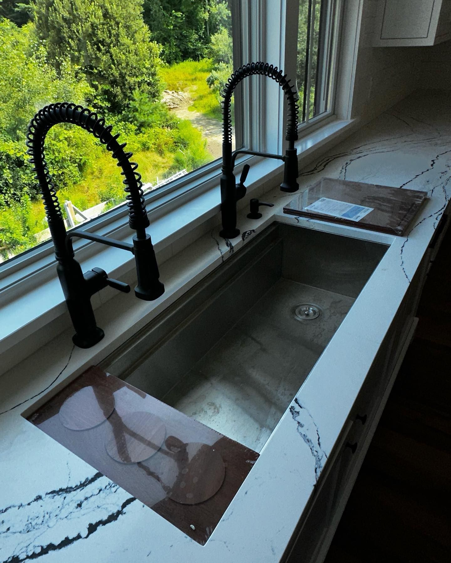 a kitchen sink with two faucets and a window