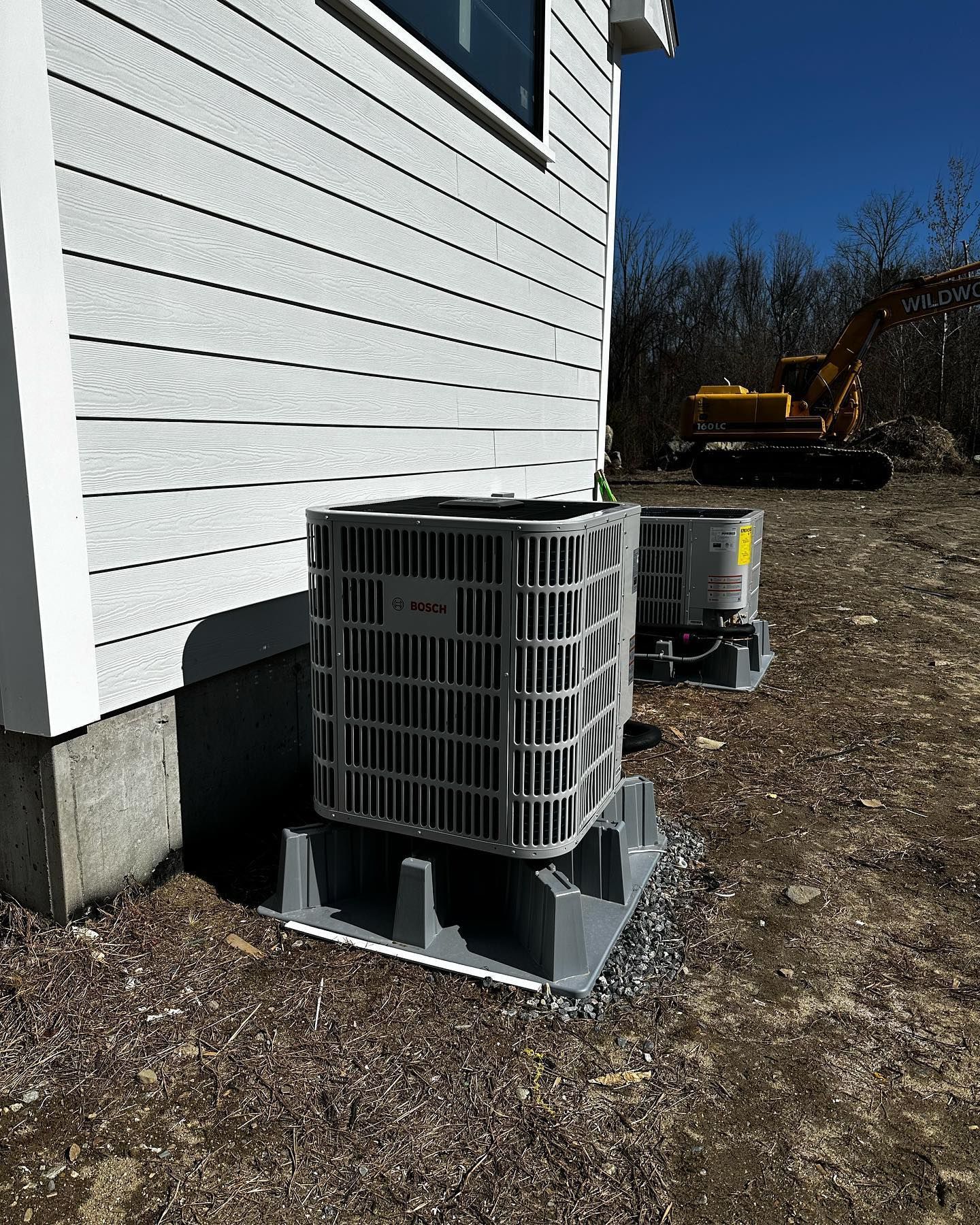 two air conditioners are sitting on the side of a house