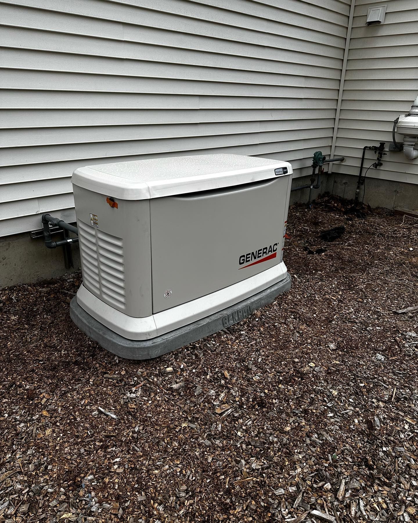 a generator is sitting on top of a pile of gravel next to a house