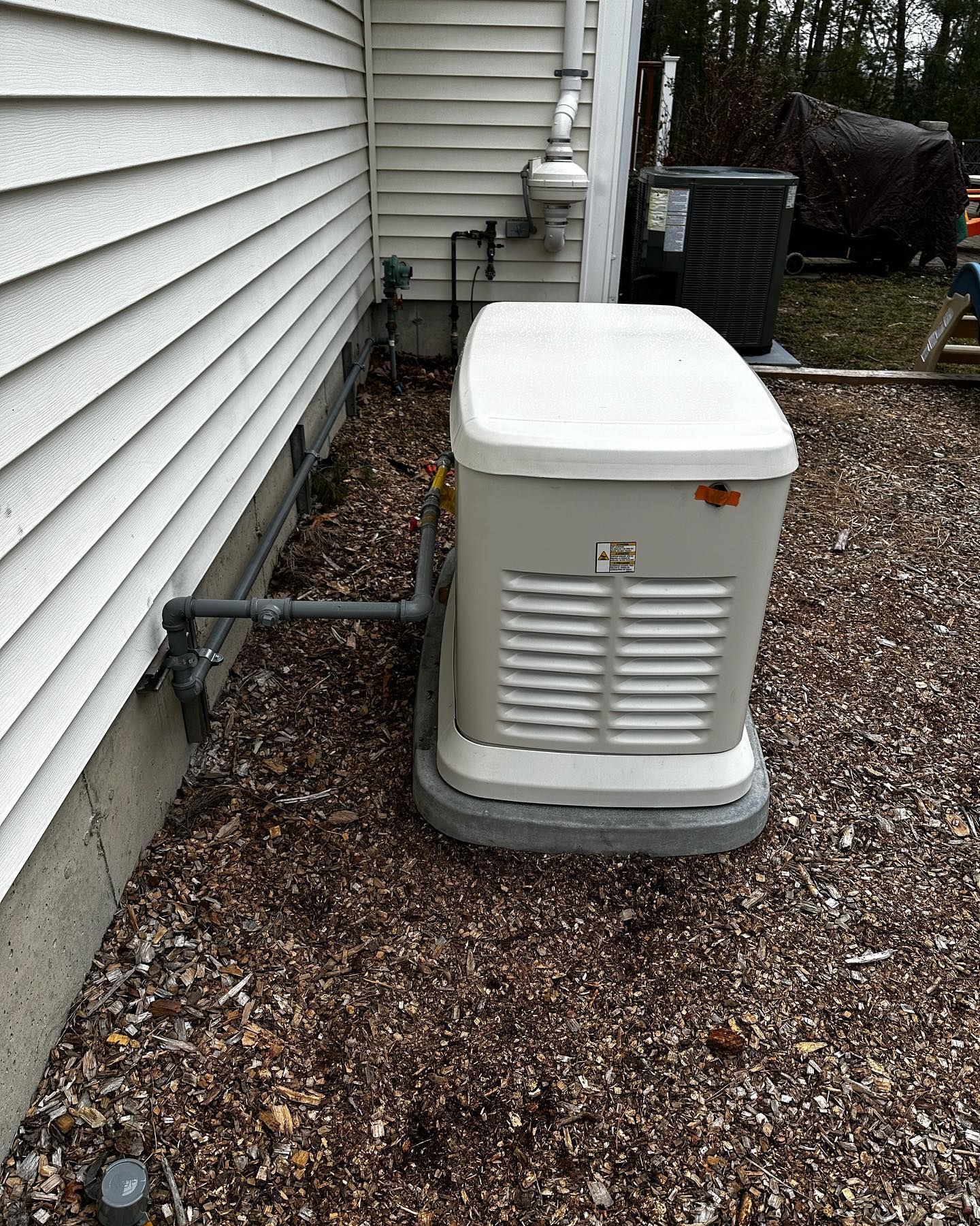 a white generator is sitting on the side of a house