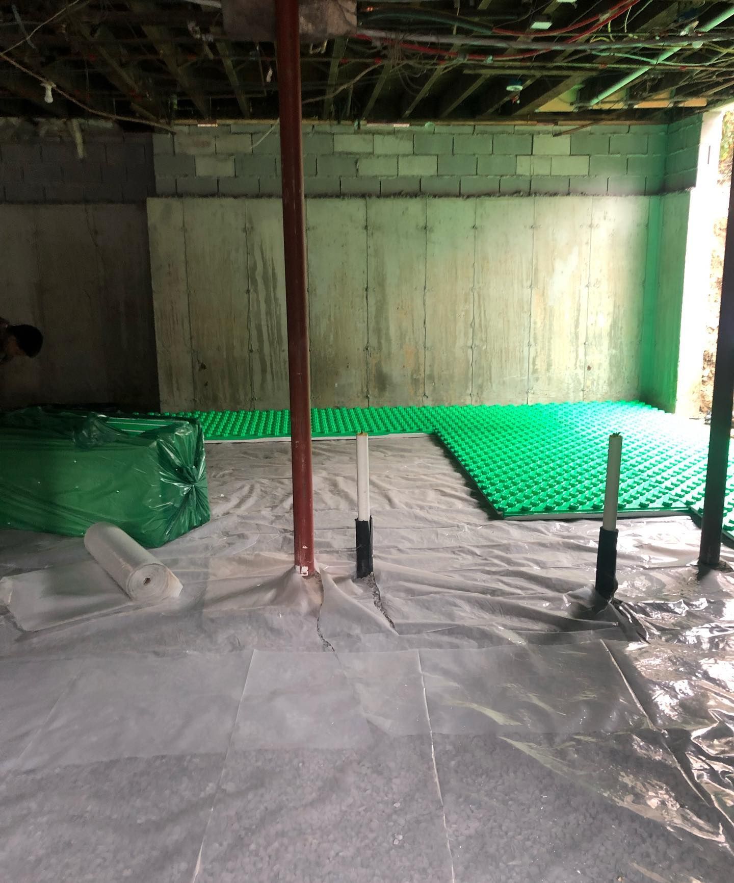 a basement with a green floor and a white tarp on the floor