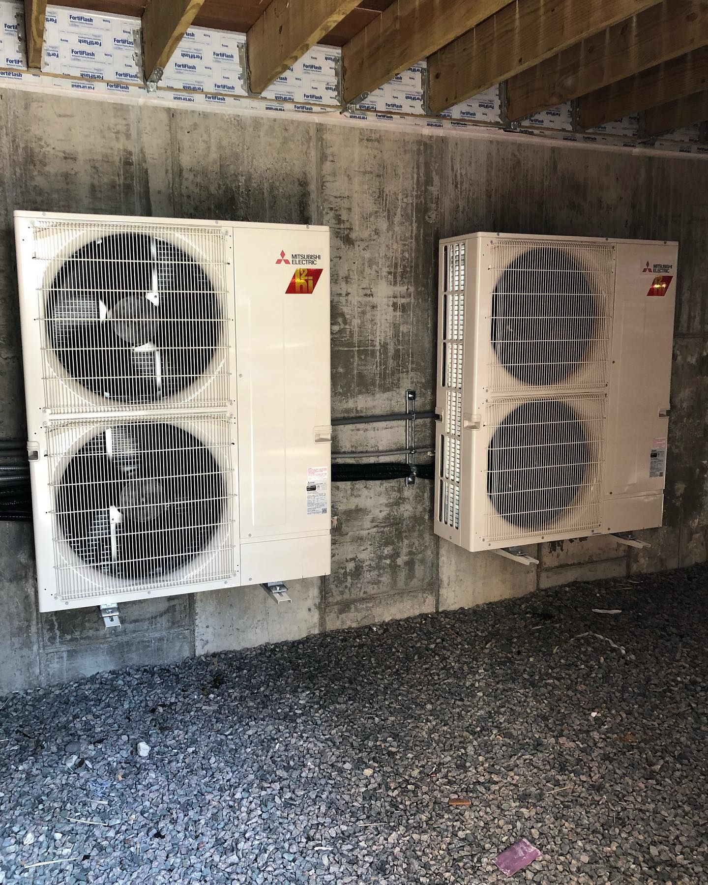 two air conditioners are hanging on a concrete wall