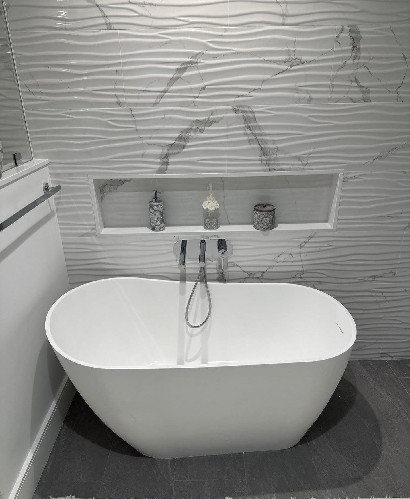 a white bathtub is sitting in a bathroom next to a marble wall