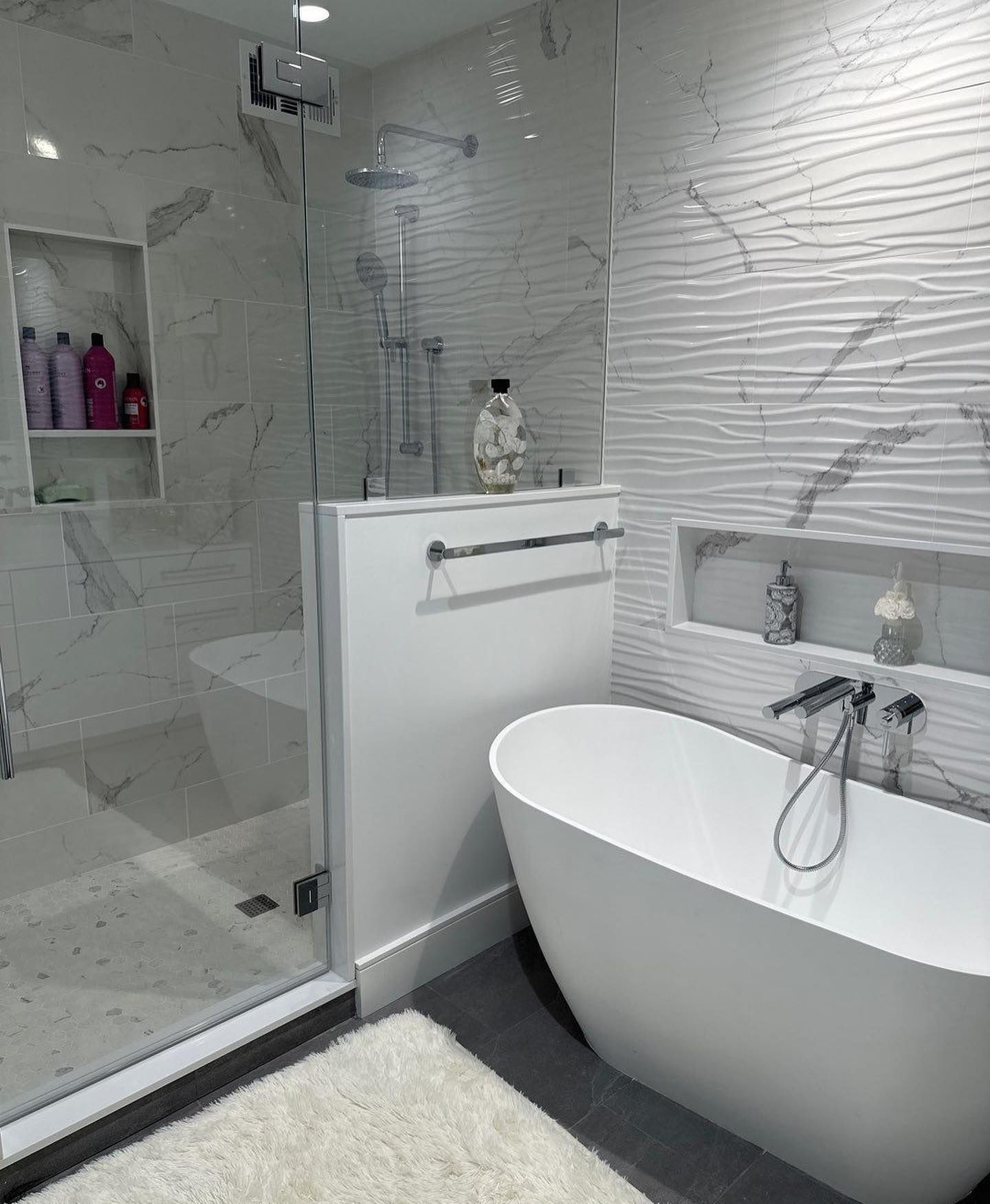 a bathroom with a tub, shower, and marble tiles