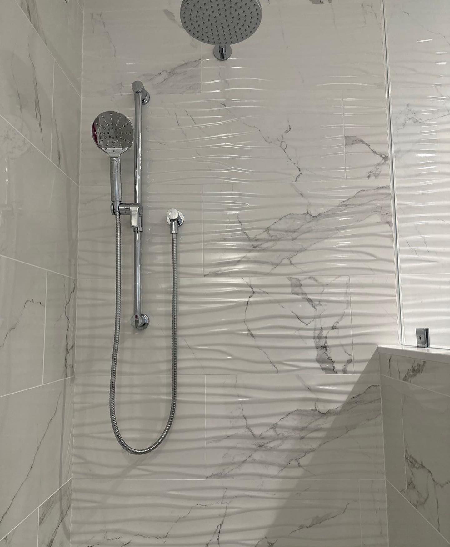 a shower with a marble wall and a shower head
