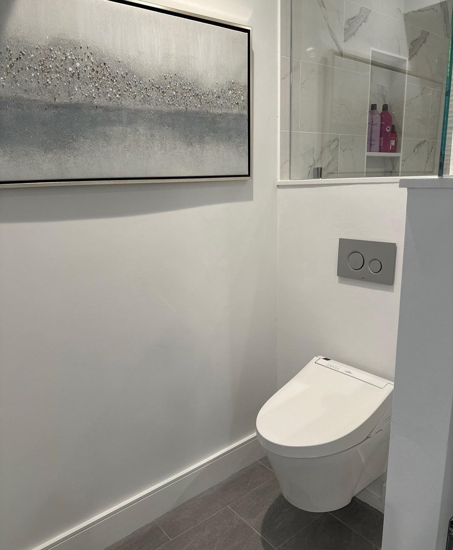 a bathroom with a toilet and a picture on the wall