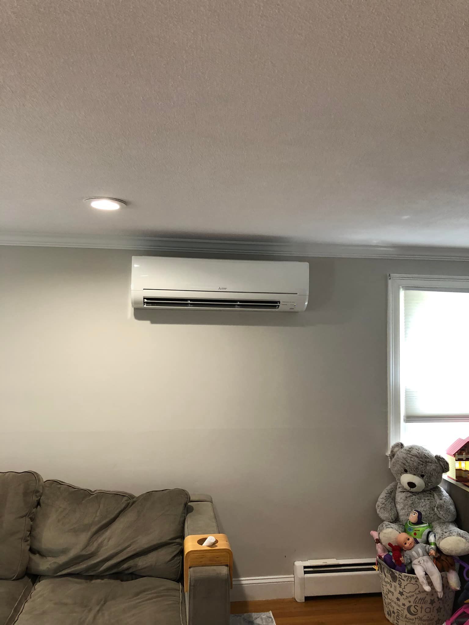 a living room with a couch, air conditioner, and teddy bears