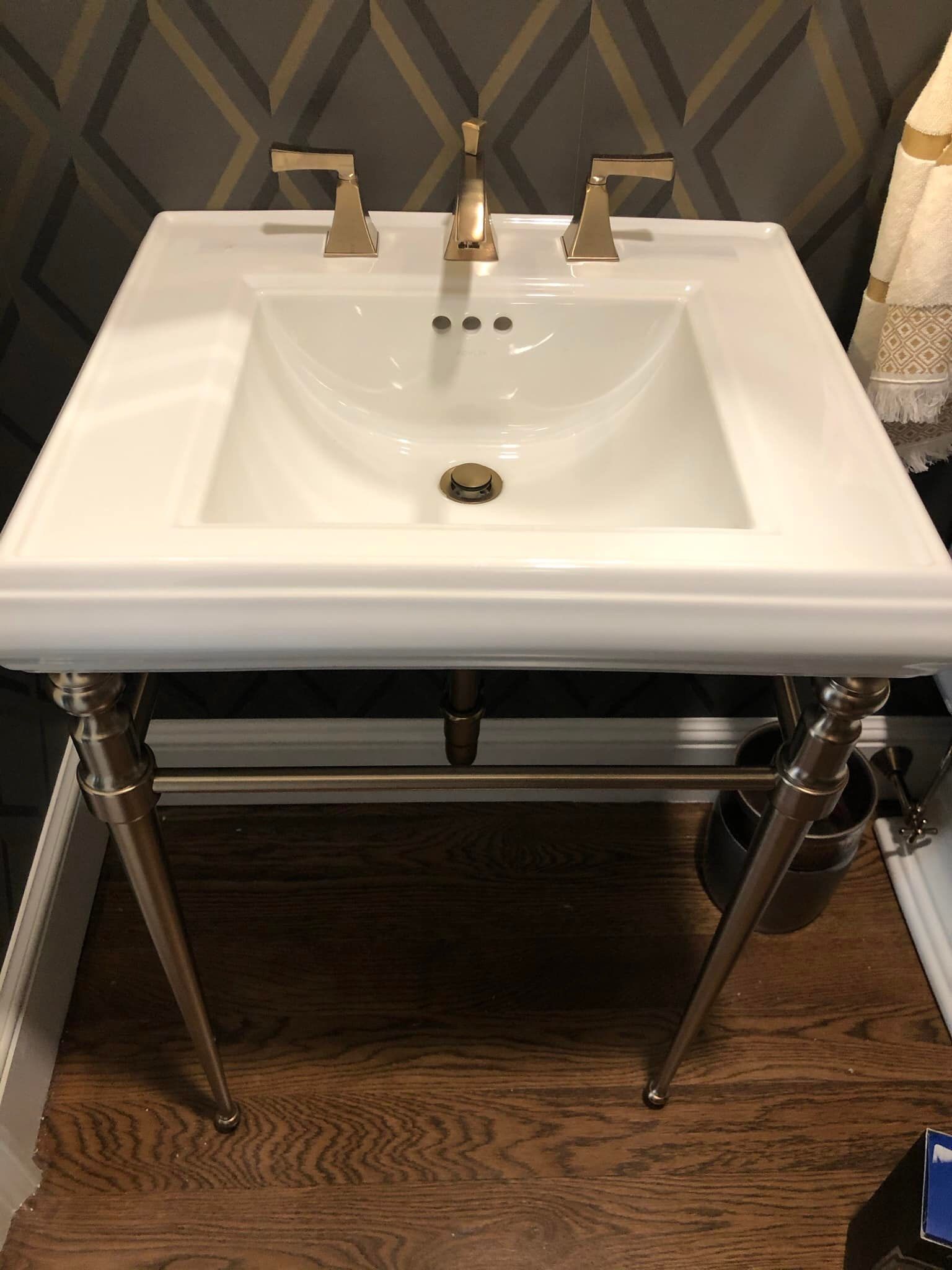 a white sink is sitting on a wooden floor in a bathroom