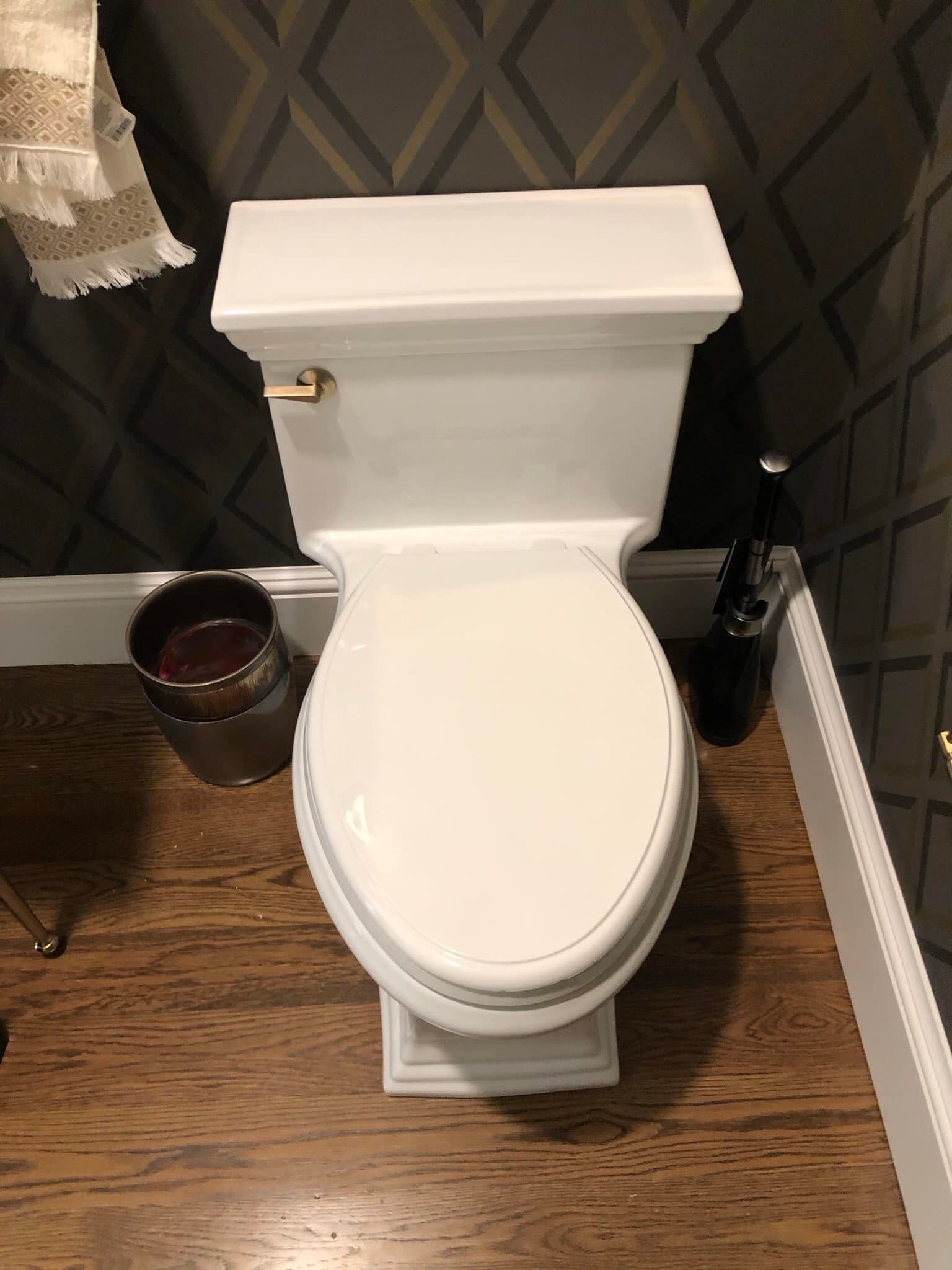 a white toilet is sitting in a bathroom next to a trash can