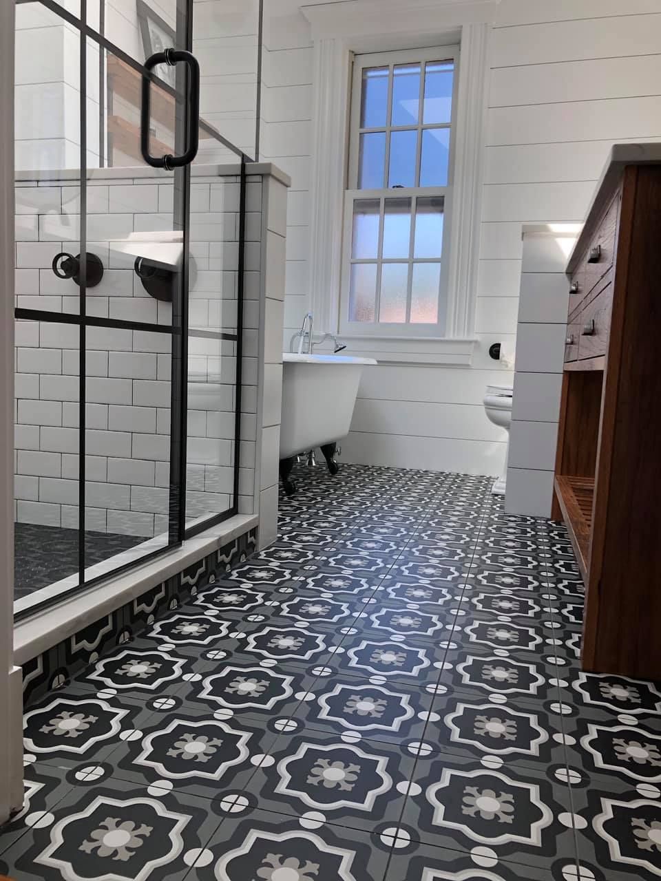 a bathroom with a black and white tile floor and a bathtub