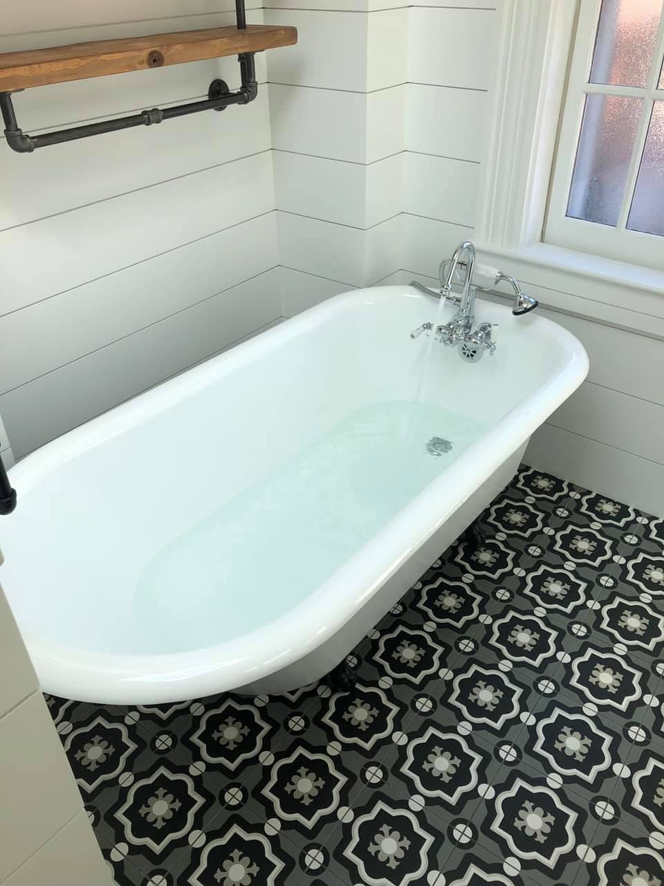 a bathtub in a bathroom with a black and white tile floor