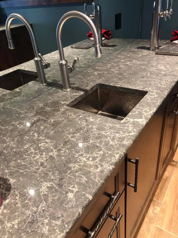 a kitchen counter with two sinks and two faucets