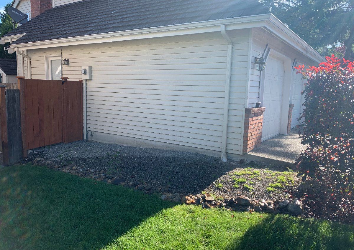 A white house with a garage and a wooden fence