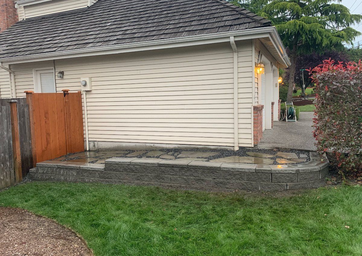 A white house with a wooden fence and a patio in front of it.