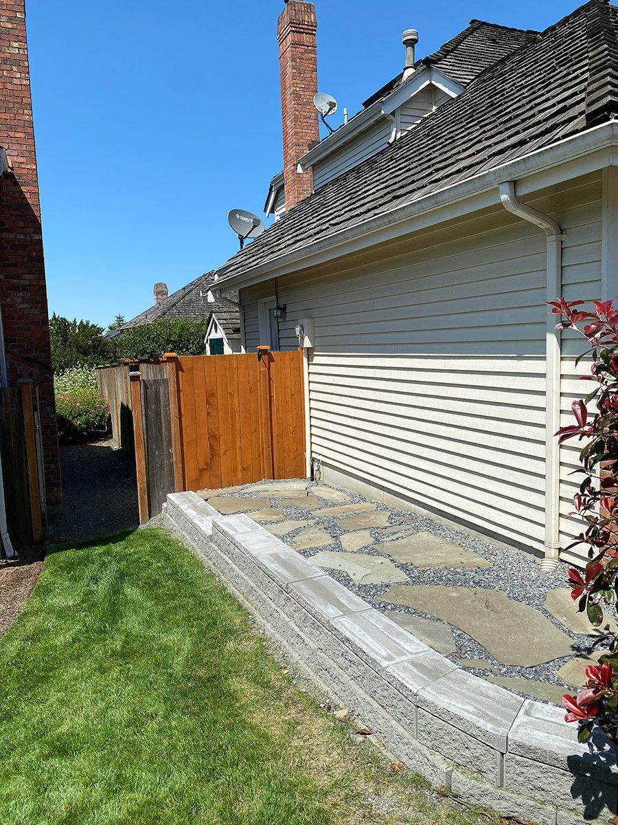 A house with a wooden fence and a stone walkway in front of it.