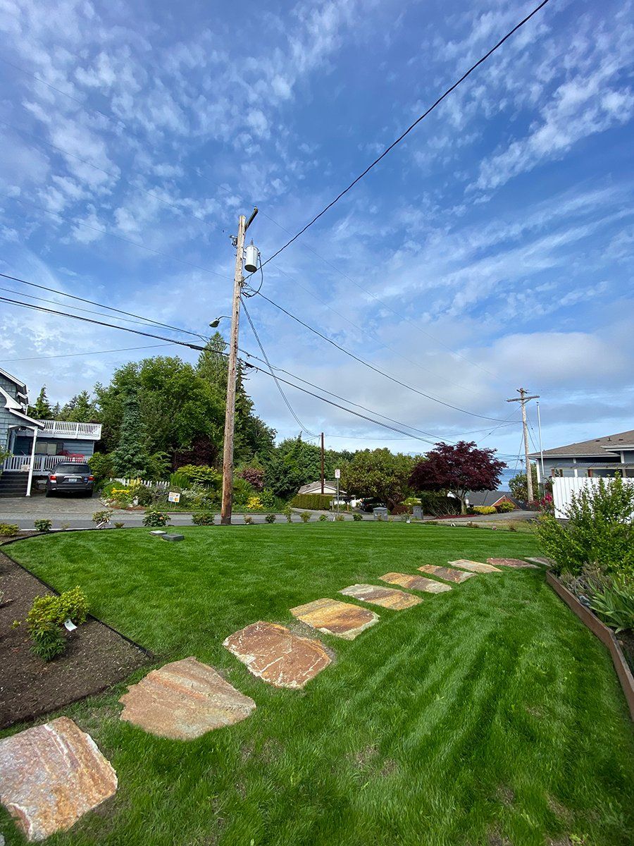 A lush green lawn with a stone walkway leading to a house.
